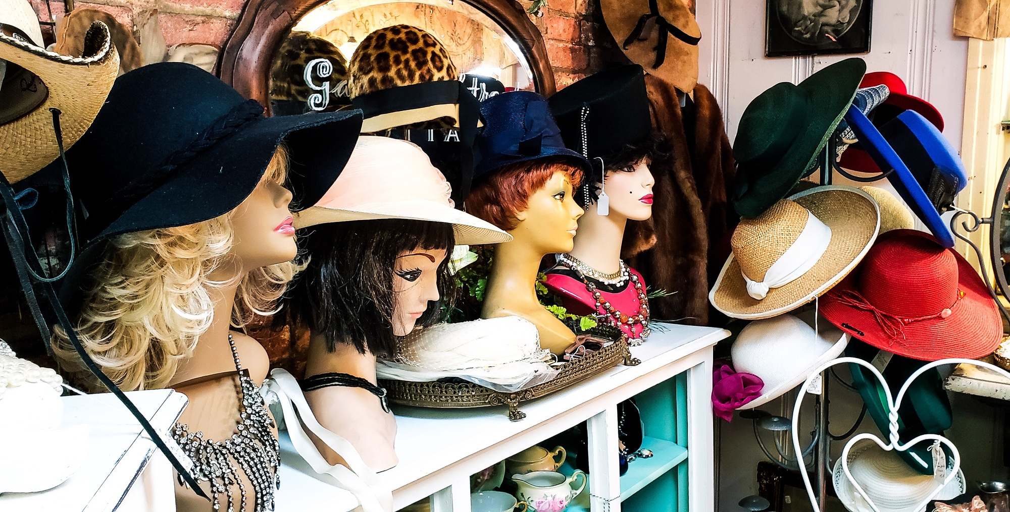 A bunch of mannequins are putting their heads together in an antique store trying to sell hats to