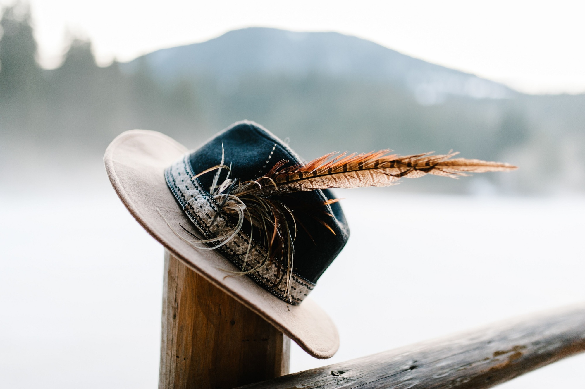 Hat with feathers handmade on a wooden fence, a column in the winter on the background